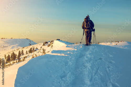 man hiker going in the mountains through the snow
