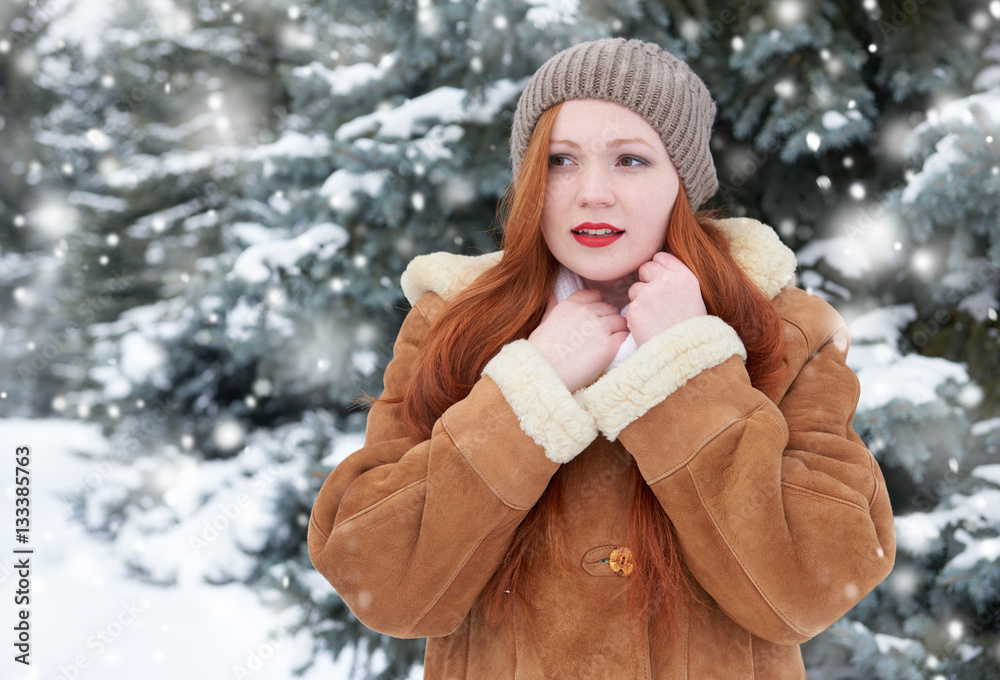 beautiful woman on winter outdoor, snowy fir trees in forest, long red hair, wearing a sheepskin coat