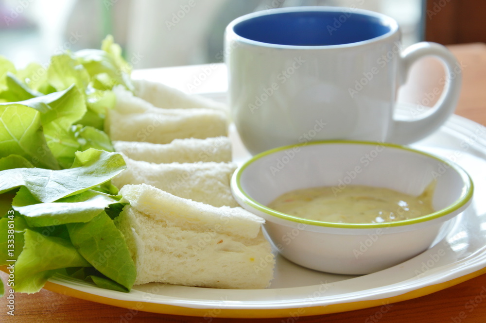 roll bread stuffed bologna and green oak with coffee cup on plate roll bread stuffed bologna and green oak with coffee cup on plate