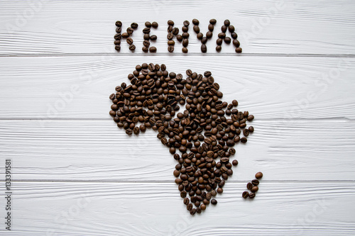 Map of the Kenya made of roasted coffee beans laying on white wooden textured background and space for text