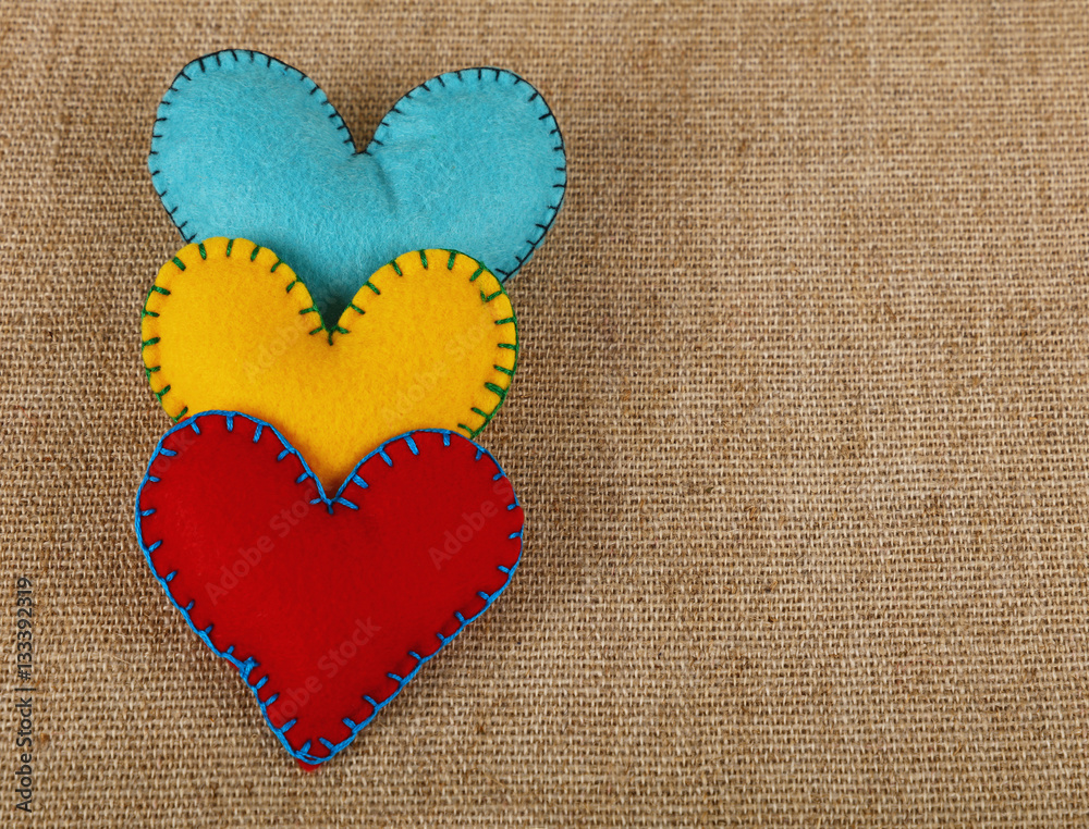 Three felt craft hearts, yellow, red and blue