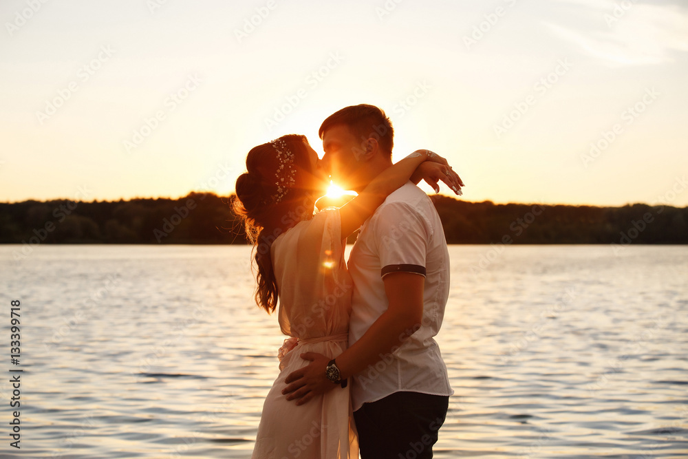 Sea love, young couple hugging and kissing on sunset. Sea adventure of young people