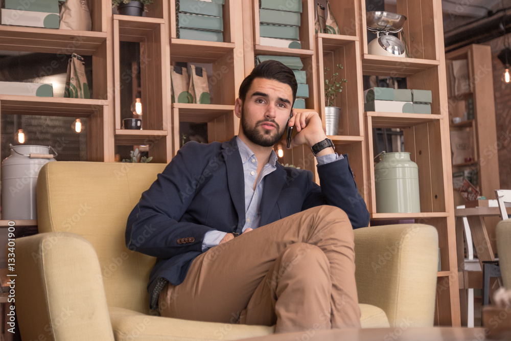 Fototapeta premium young adult man listening phone sitting indoors cafe interior