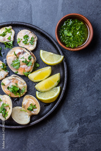 Raw clams with lemon, herbs and white wine, slate background
