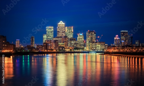 Canary Wharf business district in London at night over Thames River.