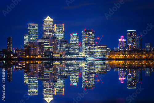 Canary Wharf business district in London at night over Thames River.
