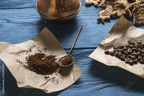 coffee beans, ground coffee, silver spoon on Kraft paper and Christmas cookies on the blue boards photo