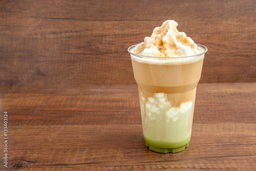 Matcha and espresso frappe in the plastic glass on wooden background