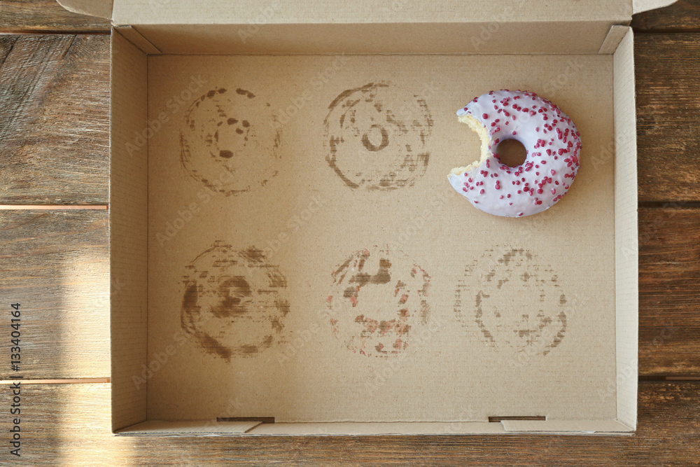 Donut with bite taken out lying in carton box Stock Photo | Adobe Stock