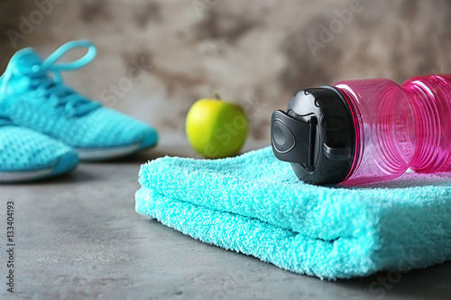 Fitness concept. Towel and bottle of water on grey table closeup
