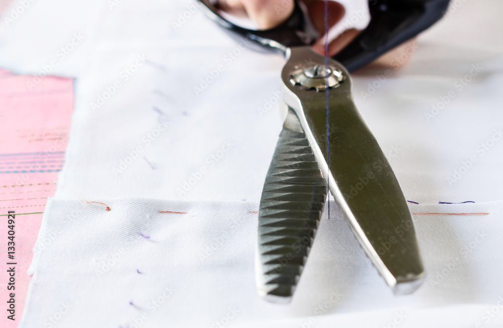 Naklejka premium Seamstress with scissors is cutting thread