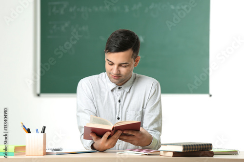 Handsome young teacher sitt...