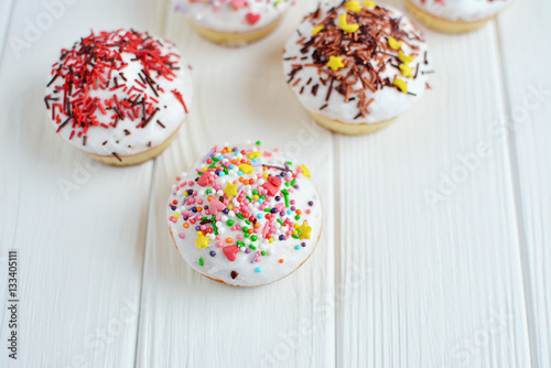 Cupcakes with white cream  and sprinkles on white background © Anna