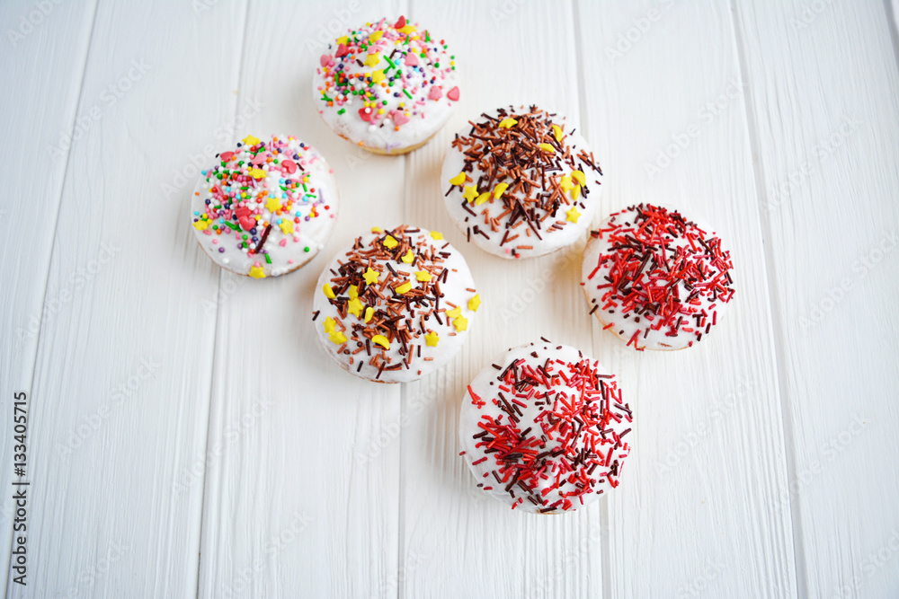 Cupcakes with white cream and sprinkles on white background Cupcakes with white cream and sprinkles on white background