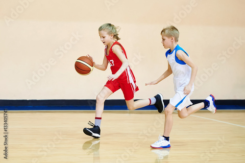 Girl and boy athlete in uniform playing basketball