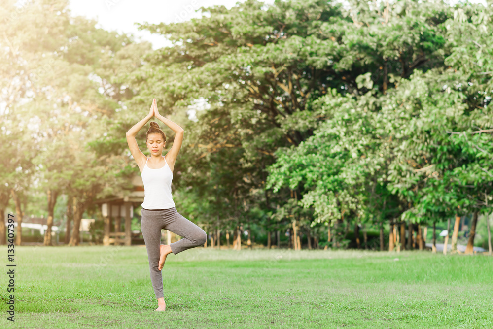 Girl do yoga pose at the park in the morning with sunlight.