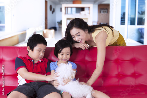 Children and mother play with cute dog