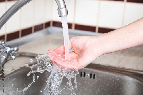 Kitchen faucet with the running water in female hand