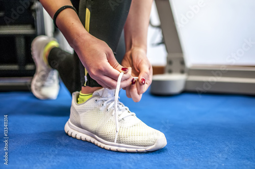 allacciarsi una scarpa da ginnastica per esercizi in palestra e per correre © pixelaway