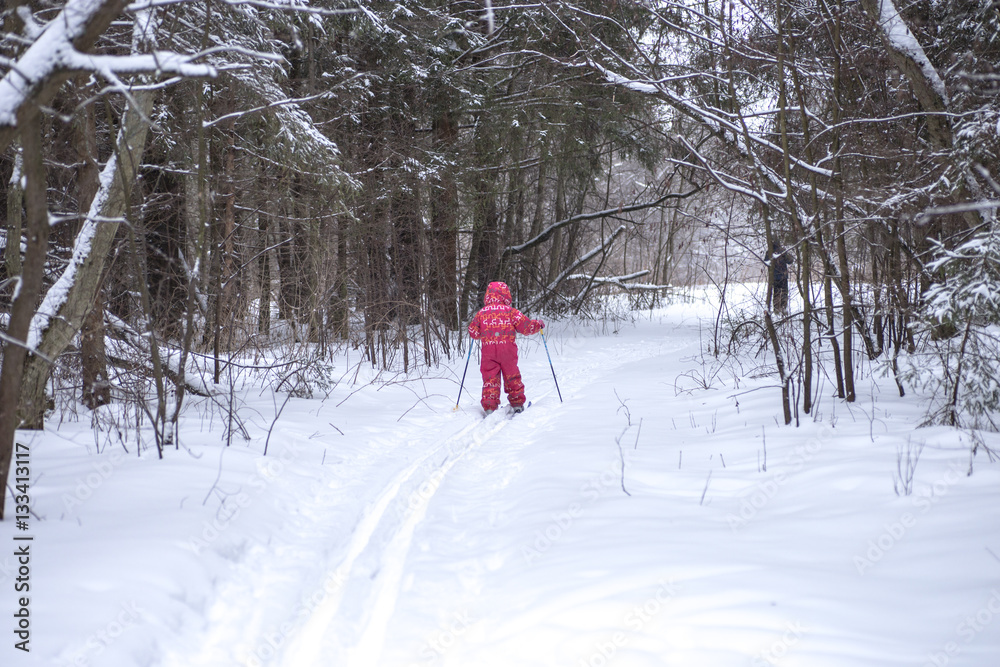 A young girl in red suit is learning skiing