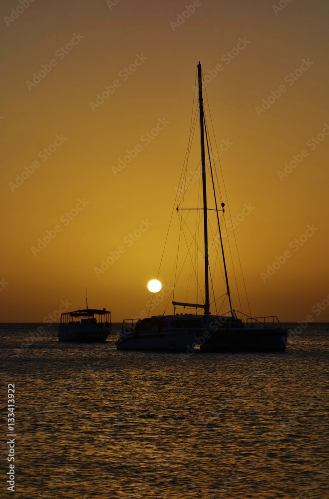 Sunset over a sailboat and the Caribbean Sea in Aruba