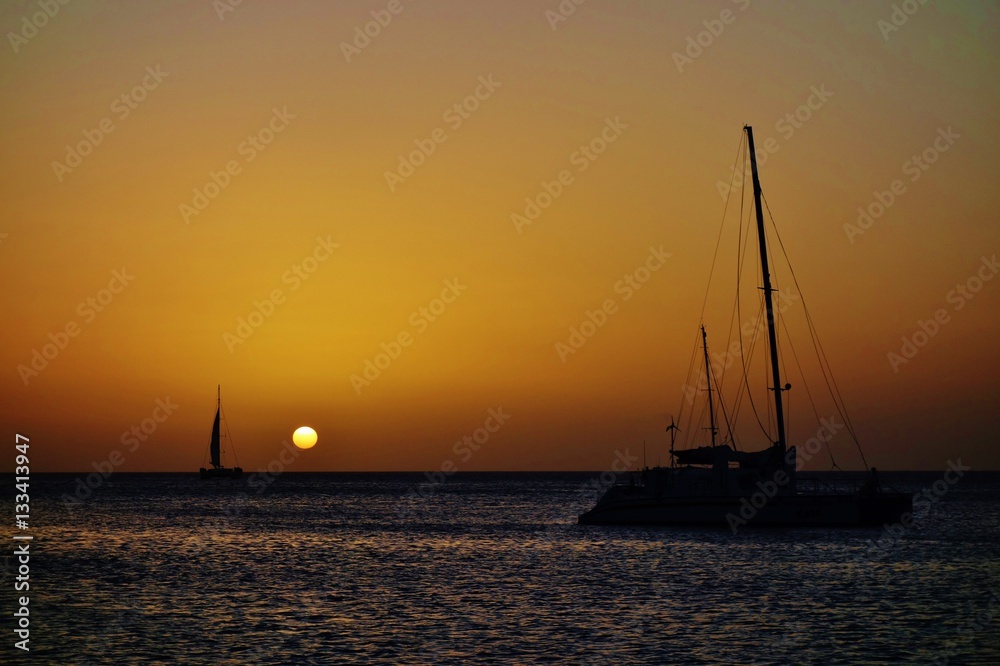 Sunset over a sailboat and the Caribbean Sea in Aruba