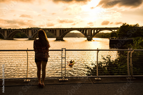 Back of young woman looking over potomac river with Francis Scott key bridge