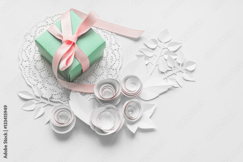 a gift on a white napkin and white paper flowers a gift on a white napkin and white paper flowers