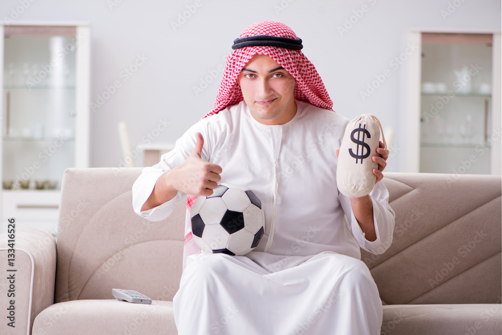 Young arab man watching football sitting on sofa Young arab man watching football sitting on sofa