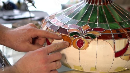 Master makes Tiffany stained glass lamp, try on a piece of glass to light form