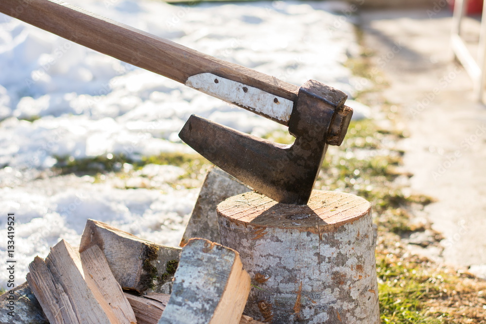 Axe stabbed in the firewood in the yard Axe stabbed in the firewood in the yard