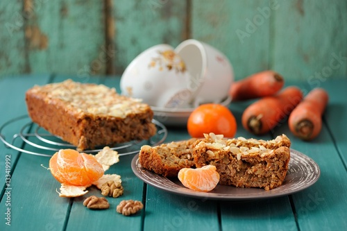 Homemade carrot cake with fresh carrots and clementines on turqu photo