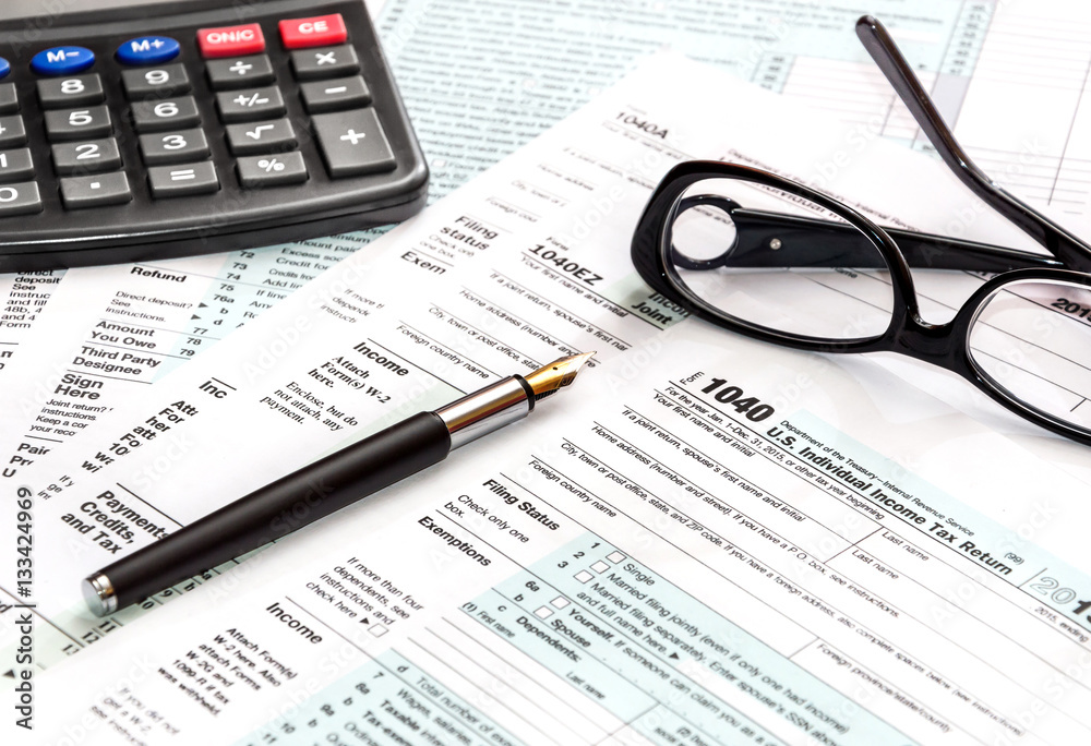 Calculator, glasses and pen on tax form 1040. Calculator, glasses and pen on tax form 1040.