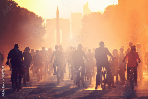 Silhouettes of people on bicycles on the sunset in the city park © sashka_lenka