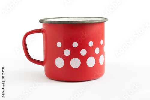 Old red enamel cup with white dots isolated on white background photo