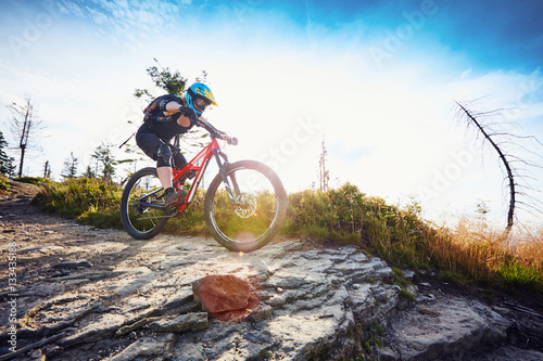 Female mountain biker riding MTB bike during sunny day in Mountains