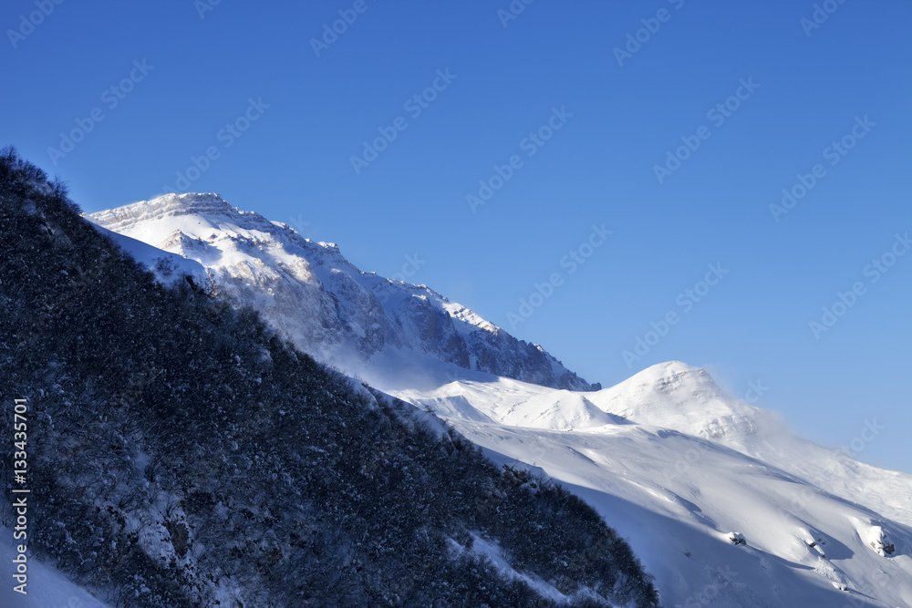 Off-piste slope and sunlight blue sky in wind winter morning