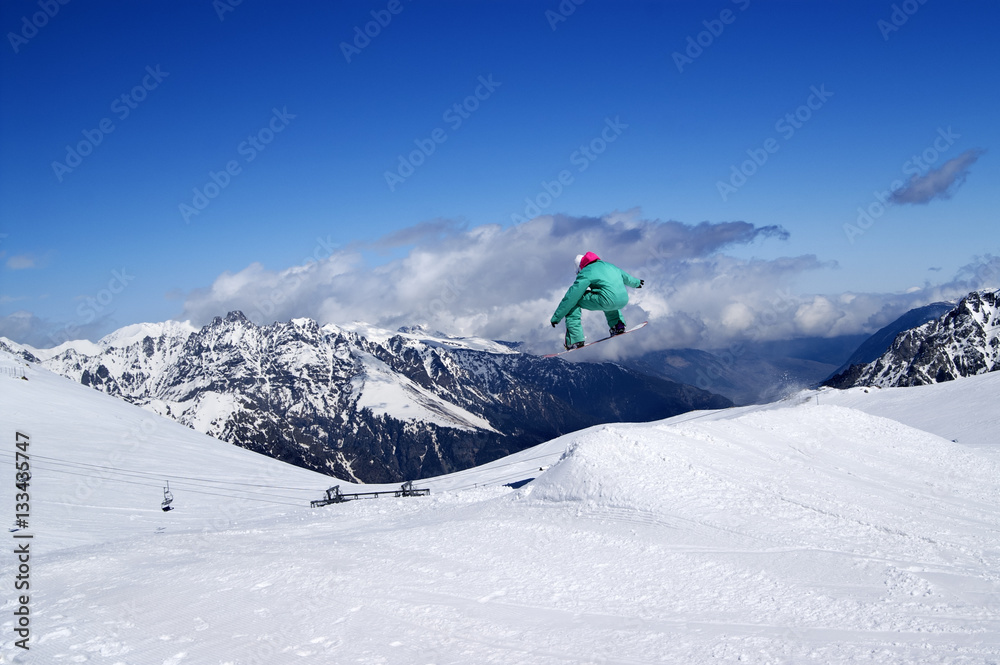 Snowboarder jumping in snow park at winter mountain on nice sunn