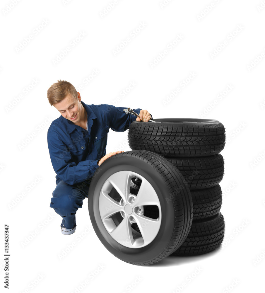 Young mechanic in uniform with wheels, isolated on white