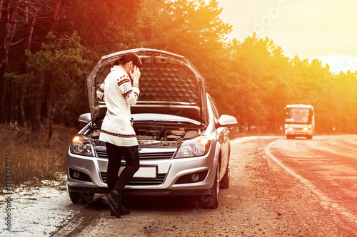 young woman standing near the broken car. The girl opened the hood and look at the engine. Refit woman car
