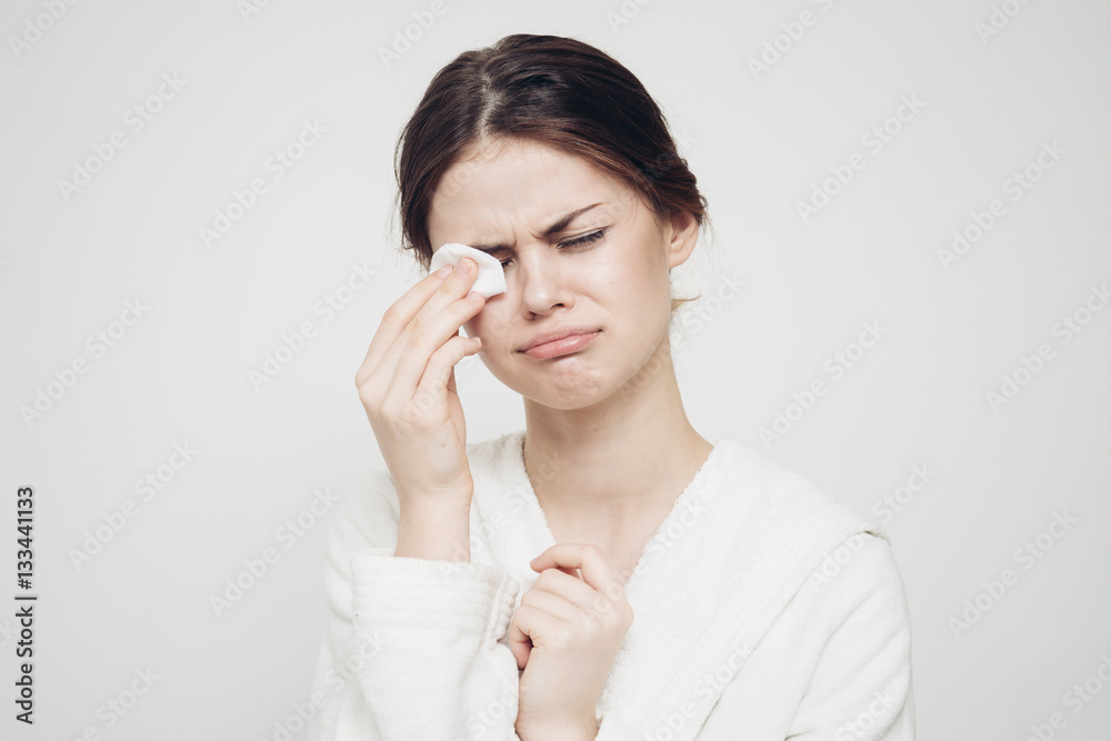 beautiful woman in a light robe wipes her face with a cotton pad, clean skin, spa beautiful woman in a light robe wipes her face with a cotton pad, clean skin, spa