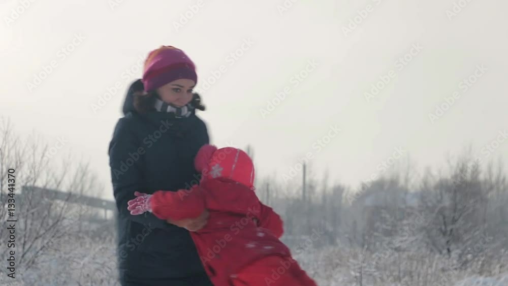 A young mother and child.Young, pretty mother and daughter, on a winter afternoon spinning with the little girl A young mother and child.Young, pretty mother and daughter, on a winter afternoon spinning with the little girl