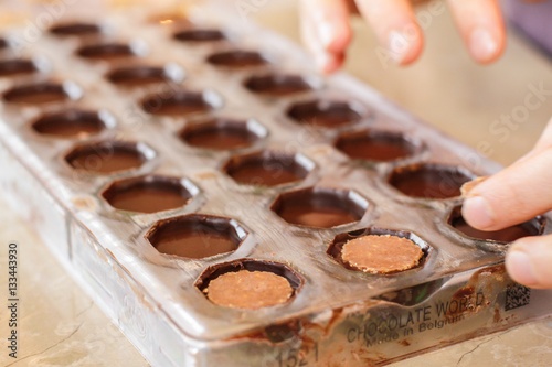 Hands working with filled chocolates in a candy mold