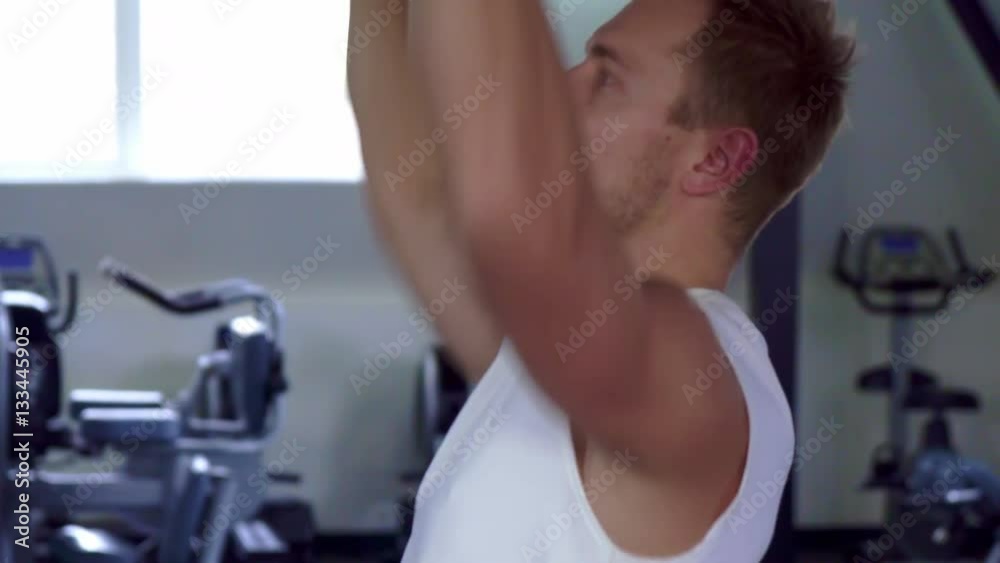 Young sportsman pushing up the barbell at the gym. Side view of caucasian male athlete lifting weight. Camera sliding from bottom up along the strong man's body Young sportsman pushing up the barbell at the gym. Side view of caucasian male athlete lifting weight. Camera sliding from bottom up along the strong man's body