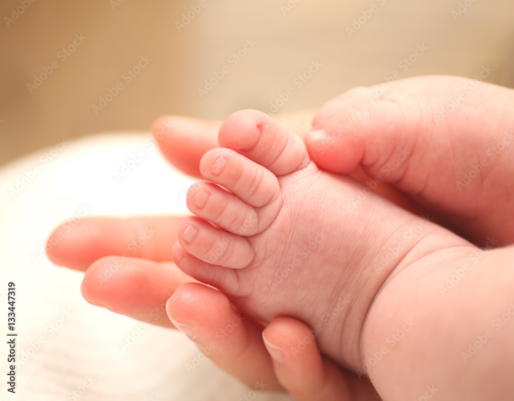 Tiny newborn baby foot in female hands.