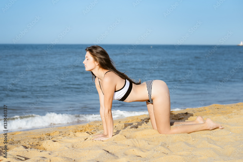 Back side view of woman doing exercises on sandy beach sunny background outdoors