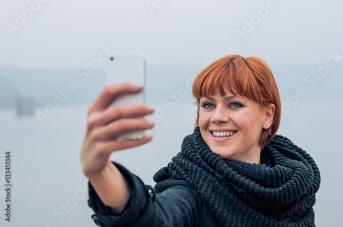 Beautiful young red hair woman taking selfie