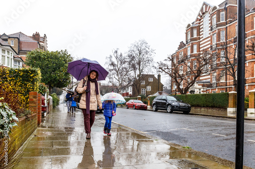 Photography People walk in winter rain in London subrub