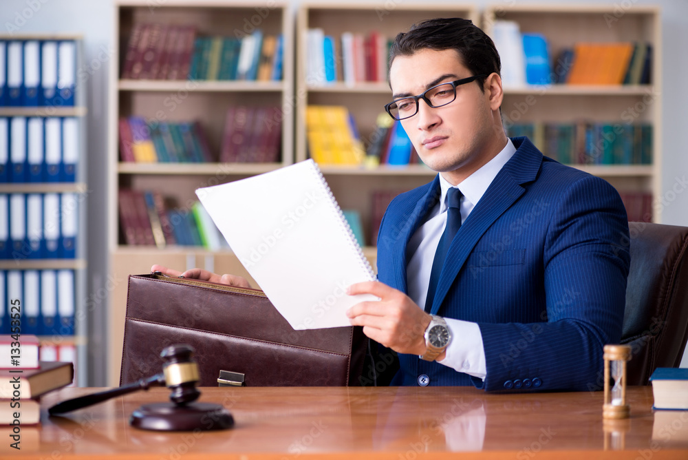Fototapeta premium Handsome judge with gavel sitting in courtroom