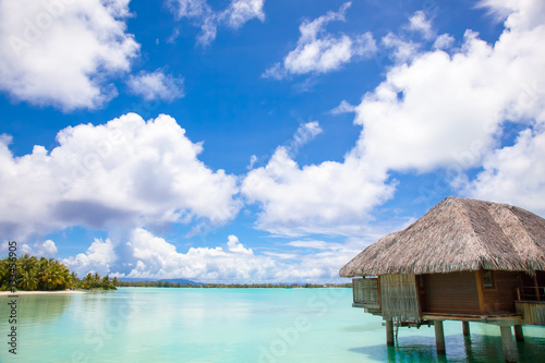 Fototapeta Naklejka Na Ścianę i Meble -  Luxury thatched roof honeymoon bungalow in a vacation resort in the blue lagoon of the Pacific island of Bora Bora, near Tahiti, in French Polynesia.  Villa over water.
